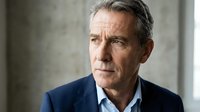 Mature Caucasian businessman in navy suit looking thoughtfully away, professional corporate executive portrait with concrete background for business content.