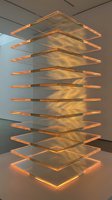 Modern stacked glass shelving unit with warm golden LED lighting creating layered geometric forms, contemporary art installation in gallery space.