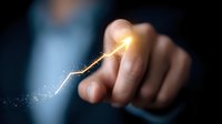 Glowing golden arrow with sparkles pointing upward touched by business person finger against dark background, representing growth and success in business.