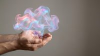 Male hand holding glowing holographic cloud shape with neon pink and blue light effects against neutral background for technology and innovation concepts.