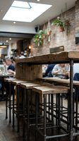 Rustic bar counter with wooden top and metal frame in modern restaurant interior with brick wall, skylights, and blurred diners in background for hospitality design.