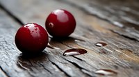 Fresh ripe cherries with water drops on rustic wooden surface in dark moody lighting, macro food photography with selective focus and bokeh effect.