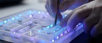 Young male hands operating illuminated DJ mixer with glowing blue and purple controls, perfect for music production, nightlife, entertainment, and audio technology concepts.