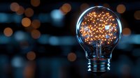 Glowing light bulb filled with magical golden sparkles and bokeh lights against dark background, creating dreamy atmosphere for creative concepts.