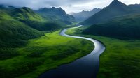 Meandering river flows through lush green valley surrounded by dramatic mountain peaks under moody cloudy sky, creating natural S-curve pattern in untouched wilderness landscape.