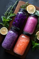 Colorful fresh smoothies in mason jars with purple cabbage, berries and citrus. Healthy detox drinks on wooden board with herbs and lemon slices.