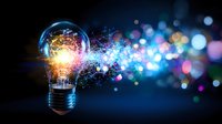 Glowing light bulb emitting colorful magical sparkles and bokeh lights against dark blue background, symbolizing innovation and creative energy flow.