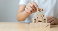 Business professional building wooden blocks with strategy icons representing teamwork, innovation, and growth planning for corporate development.