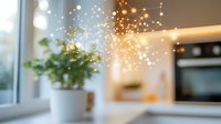 Dreamy bokeh lights and sparkles overlay on blurred modern kitchen interior with white flowerpot on windowsill, creating magical cozy atmosphere.