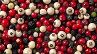 Fresh mix of red and white peppercorns with black peppercorns scattered on dark background, macro food photography for culinary and spice design concepts.
