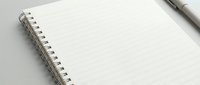 Open spiral notebook with dotted grid pages and pen for writing, planning, journaling, note-taking, sketching, bullet journaling and office work.