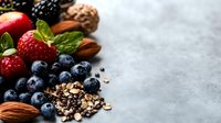 Fresh berries, nuts and seeds arranged on gray concrete background with copy space. Healthy organic superfood mix for nutritious eating and snacking.