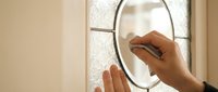 Woman applying makeup using round magnifying mirror in bright bathroom interior for daily beauty routine and skincare preparation.