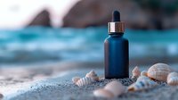 Navy blue cosmetic dropper bottle on sandy beach with seashells against blurred turquoise ocean waves, wellness and natural skincare concept.