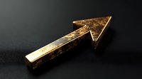 Golden metallic arrow pointing upward on dark background, symbolizing growth, success, and forward movement in business and finance concepts.