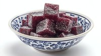 Fresh homemade burgundy wine gummy candies with sugar coating served in traditional blue and white porcelain bowl on white background, isolated.