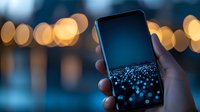 Hand holding smartphone displaying glowing blue dots against blurred bokeh city lights background, creating modern technology atmosphere.