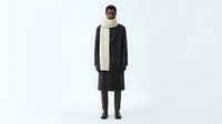 African American woman wearing black coat and cream turtleneck sweater, standing against white background for fashion and apparel design use.