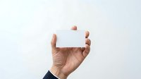 Mature male hand holding blank white card against neutral background, isolated on white for business, marketing, and design mockup purposes.