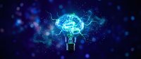 Glowing brain inside light bulb with electric energy and bokeh lights on dark blue background representing creativity and innovation concepts.