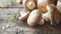 Fresh brown mushrooms with water drops on rustic wooden surface in natural light, selective focus creates atmospheric food photography mood.