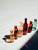 Colorful glass bottles arranged in row casting shadows on white surface, creating minimalist composition for food and beverage marketing.