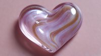 Marble effect heart shape with swirling pink and gold patterns on soft pink background, romantic design element for valentines and love themes.