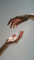 Elegant hands reaching toward each other against soft gray background, symbolizing connection, support, and human relationship.