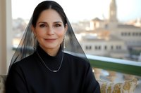 Professional businesswoman in black attire smiling confidently at camera with urban cityscape background for corporate marketing and business success concepts.