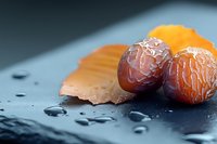 Fresh dates and dried apricots on dark slate surface with water droplets for healthy snacking and natural sweetness in culinary photography.