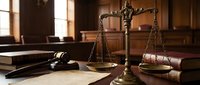 Scales of justice with gavel and law books in courtroom setting. Legal concept for attorney services, judicial system, and legal proceedings.