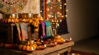Traditional Hindu prayer altar with brass bowls, marigold garlands, colorful fabrics and glowing oil lamps creating sacred spiritual atmosphere for worship.