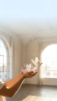 Hands releasing white paper birds in sunlit room with arched windows symbolizing freedom hope and new beginnings for wellness and spiritual concepts.