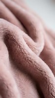 Soft pink fleece fabric with plush texture creating cozy folds and waves for home decor and fashion design projects.