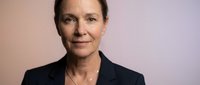 Professional middle-aged Caucasian businesswoman in dark blazer with confident expression against neutral background for corporate presentations.