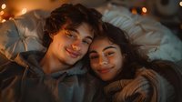 Young diverse couple lying close together sharing intimate moment in warm evening lighting, expressing genuine happiness and romance. Cozy atmospheric portrait.