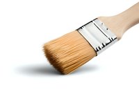 Clean paintbrush with wooden handle and synthetic bristles isolated on white background, metal ferrule detail shown in close-up diagonal composition.