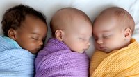Peaceful sleeping multiracial babies wrapped in colorful knitted blankets lying together. Sweet newborn portrait showing diversity and innocence in childhood.