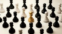 Golden chess king stands out among black and white pawns on neutral background representing leadership, strategy, and standing out from crowd in business concept.