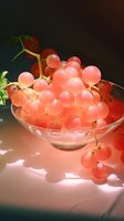 Fresh pink grapes in glass bowl with dramatic lighting casting soft shadows, showcasing translucent fruit texture for food photography.
