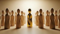 Golden wooden figure stands out among crowd of identical brown figures representing leadership, uniqueness and standing apart from others.