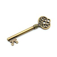 Vintage brass key with ornate decorative head featuring intricate scrollwork design isolated on white background for antique and security concepts.