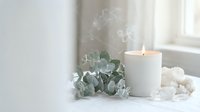Minimalist spa wellness scene with burning candle, eucalyptus leaves and white coral on windowsill creating peaceful relaxation atmosphere for home decor.