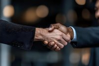 Close-up of diverse business professionals shaking hands with blurred bokeh background, symbolizing partnership, agreement, and successful negotiation.