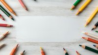 Colorful wooden pencils arranged in circular frame on white wooden background with copy space in center, flat lay composition for creative design.