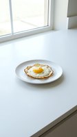 Single fried egg with golden yolk on white plate in bright minimalist kitchen setting for breakfast and cooking concepts.