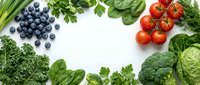 Fresh organic vegetables and blueberries arranged in circular frame on white background. Healthy eating concept with spinach, broccoli, tomatoes and greens.