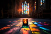 Glowing candle in dark church interior with colorful light from stained glass windows creating rainbow reflections on stone floor, spiritual atmosphere.