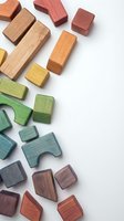 Colorful wooden building blocks and puzzle pieces scattered on white background for educational toys and children development activities.