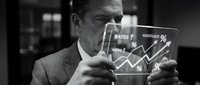 Middle-aged Caucasian male businessman in suit holding tablet displaying financial charts with rising mortgage rates graph, black and white stock photo for finance and real estate concepts.